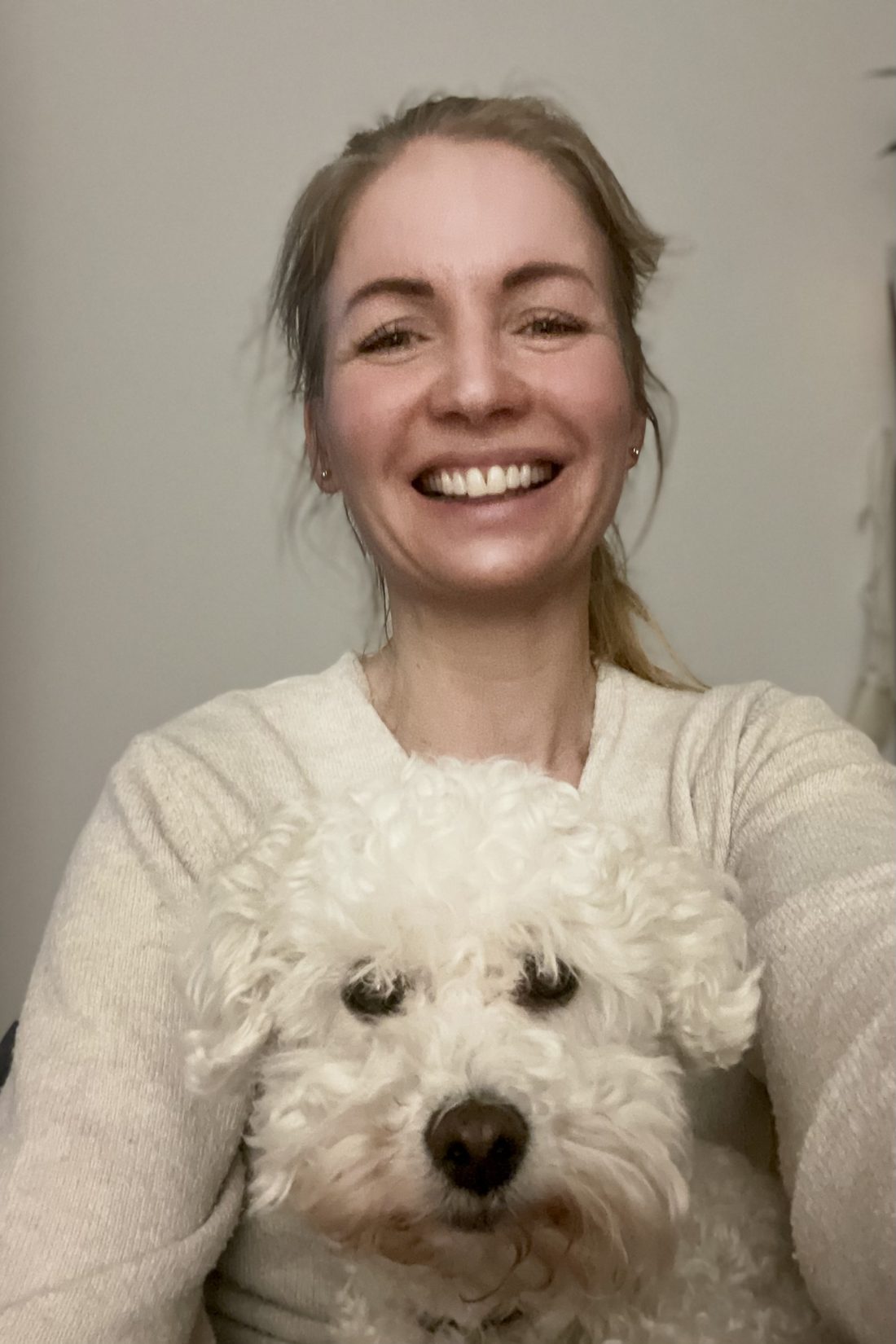 Melanie Thalmann lacht, im Arm ihren weißen Hund