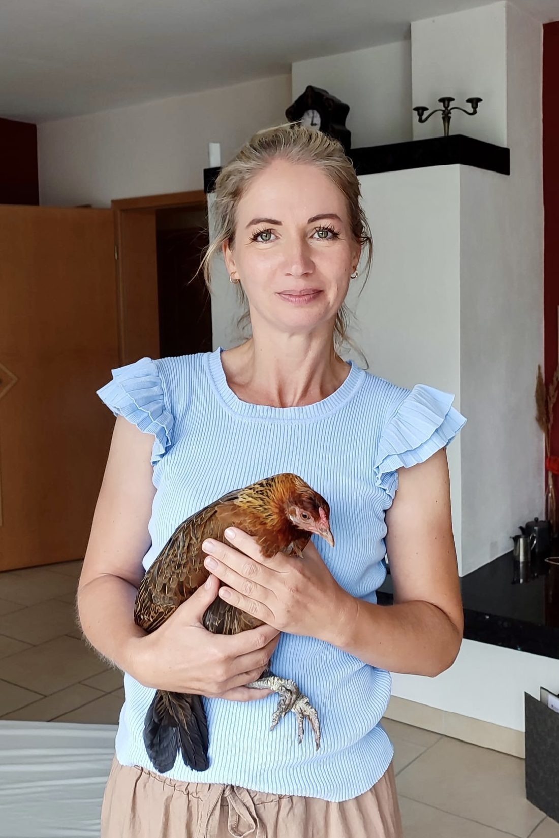 Melanie Thalmann hält lächelnd ein braunes Huhn im Arm